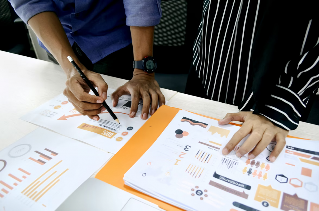 Dashboard printouts on desk, with hands hovering over with data analyst skills